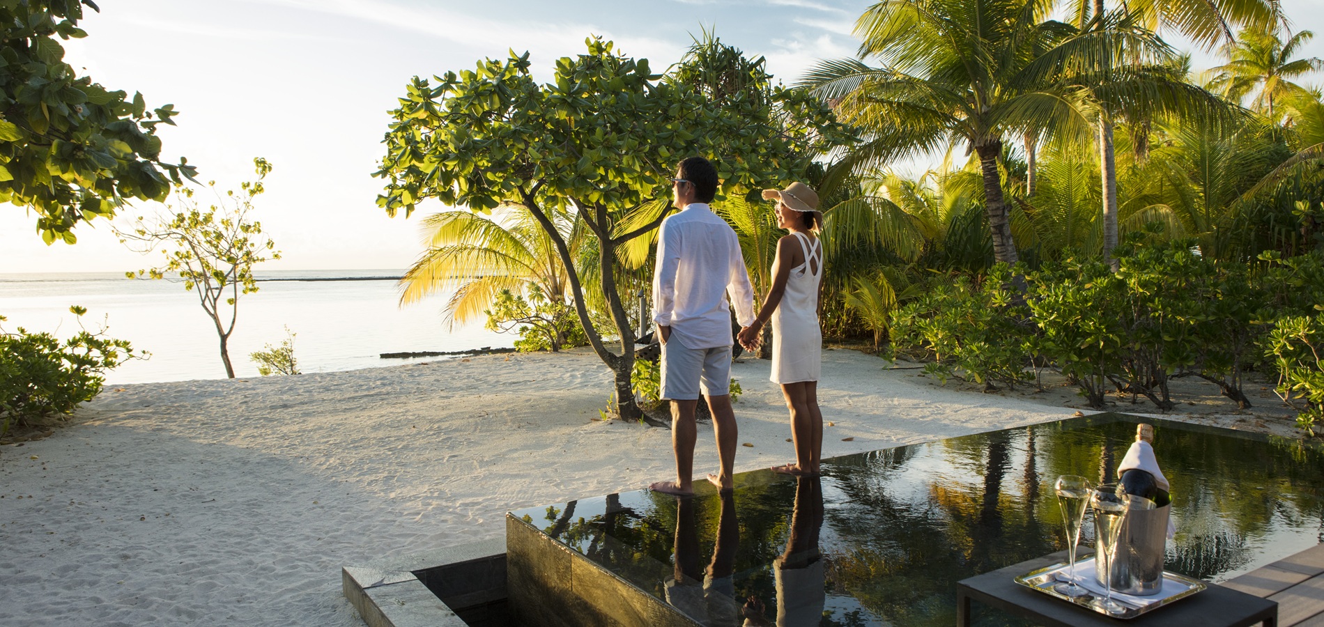 Jeune couple admirant le lagon lors d'un itinéraire lune de miel Polynésie au coucher du soleil