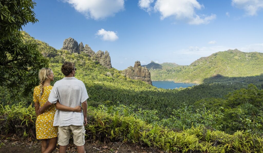 Couple enlacé admirant la vue sur les montagnes verdoyantes et une baie de Nuku Hiva